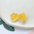 Vue macro de breloques pattes de chat en résine jaune pailletée sur un support blanc avec feuilles - Jaune