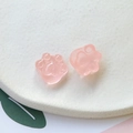 Vista macro de dijes de pata de gato en resina rosa translúcida con purpurina para DIY - Rosa
