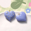 Macro detail of lavender resin heart charms with rhinestones and gold metal ring loops - Purple