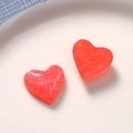 Close-up of heart-shaped red resin charms with fine silver glitter for DIY jewelry crafts - Red