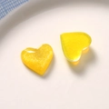 Macro shot of two yellow heart resin glitter charms for DIY jewelry and hair accessories - Yellow