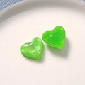 Macro shot of green heart-shaped resin charms with shimmering glitter for DIY crafting - Green