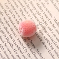 Detailed macro shot of a pink-orange flocked spherical stud earring with subtle glitter - Orange
