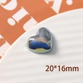 Macro shot of a 20x16mm laser-cut iridescent blue resin heart bead on a white ceramic tray - Small Heart Style / 1 Piece / Fantasy Blue