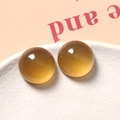 Macro-opname van twee ronde amberkleurige hars cabochons op een witte keramische schaal - 1 Stuk / Bruin