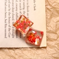 Macro shot of square transparent resin charms with red and orange beads for DIY jewelry - Square