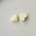 Primer plano de dijes de corazón de resina amarillo crema con acabado brillante sobre cerámica - Blanco lechoso