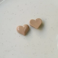 Primer plano de dijes de resina en forma de corazón rosa nude sobre bandeja de cerámica - Chocolate