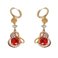 Boucles d'oreilles gourde dorées avec zircon rouge et symbole de chance sur fond blanc - Boucles d'Oreilles Créoles Calebasse Noeud Zirconia Rouge