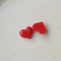 Macro-opname van twee glanzende rode hars hartjes op een wit keramisch bord decoratie - Rood
