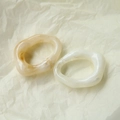 Detailed view of irregular resin drop charms with ink marble texture on a wrinkled background - Beige
