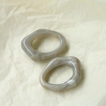 Macro detail of irregular resin hoop earrings with grey marble texture on yellow background - Smoke