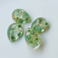Macro shot of teardrop resin charms with green dried flowers and gold foil details - Green