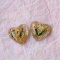 Macro detail of heart-shaped resin charms with gold leaf and dried flowers for DIY jewelry - Heart