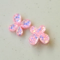Detalle macro de colgantes de mariposa en resina rosa con purpurina irisada para manualidades - Rosa