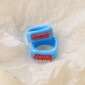 Detailed view of two blue resin rings with 3D red Happy text on textured paper background - Happy Letters Style / Sky Blue