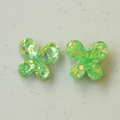 Vista macro de dijes de mariposa en resina verde con lentejuelas brillantes para joyas DIY - Verde