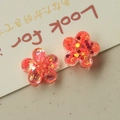Makroaufnahme von Harzblumenanhängern mit orangefarbenen und goldenen Pailletten für DIY - Wassermelonenrot
