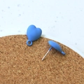 Macro detail of matte blue heart earrings showing smooth paint finish and metal posts - Blue