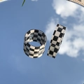 Détail de deux bagues en résine à damier noir et blanc reflétant le ciel bleu clair - Noir et Blanc