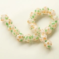 Macro detail of handmade glass beads with orange floral pattern and green leaves - 1 Piece/Pack / White