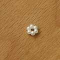 Macro shot of white acrylic pearl flower charm for DIY earrings on a wooden background - Small Pearl Circle