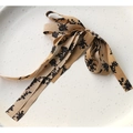 Detalle de lazo de cinta vintage color champán con elegante estampado floral negro - Color Té con Leche