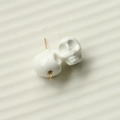 Close-up of white 3D skull resin charms with gold metal hooks for DIY jewelry making - White