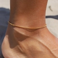 Dettaglio della cavigliera Figaro placcata oro 18 carati indossata sulla spiaggia al sole - Catena Minimalista Ultra Sottile (Style 06)