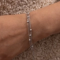 Detaillierte Nahaufnahme eines dreilagigen Perlenarmbands in Silber auf dem Handgelenk - Silver Snake Chain Layered
