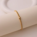 Detail eines 18K vergoldeten Perlenarmbandes mit Fokusperle auf einem Displayständer - Minimalistischer Goldperlen-Stil