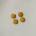 Detail of four yellow fabric-covered round buttons with woven texture for coats - Tan