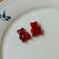Macro shot of two red translucent jelly bear resin charms on a white ceramic plate - Burgundy