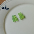 Close-up of translucent lime green resin gummy bear charms on a decorative white porcelain plate - Fruit Green