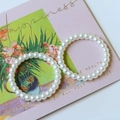 Detailed view of two faux pearl elastic bracelets on decorative card with artistic floral art - Large Hollow Ring (Artificial Pearl)