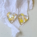 Macro shot of heart-shaped resin charms with gold foil and yellow flowers for DIY jewelry - Yellow