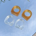 Minimalistische geometrische acryl ringen in amber en helder op een spiegelend oppervlak - Transparant