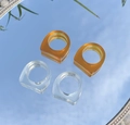 Set van vier brede geometrische harsringen in amber en transparant op een spiegel - Amber