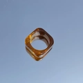 Macro view of square amber resin ring with tortoise shell patterns on reflective surface - Amber