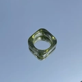 Macro shot of minimalist square resin ring in transparent ink green on reflective surface - Green