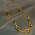 Gold flat snake chain necklace with five turquoise sunburst pendants on silk texture - Round Style