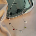 Minimalist butterfly necklace with colorful beads on a silver chain displayed on satin - Silver