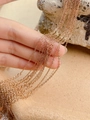 Détail d'une chaîne à maillons dorée rose empilée sur une surface chaude texturée - Chaîne de croix or rose