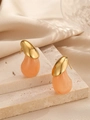 Vue détaillée de boucles d'oreilles goutte en métal doré et résine pêche sur du satin élégant - Orange
