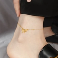 Detail der Titanstahl-Fußkette mit goldenem Schleifenanhänger und Perlen am Knöchel - Schleifen Fußkettchen (Gold - Fein)