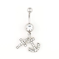 Macro detail of navel ring with silver cross and anchor charms inlaid with white zircon - White