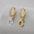 Macro view of asymmetrical gold hoop earrings with teardrop gem and crystal letter C - Copper / Gold-Letter C