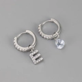 Detail van zilveren asymmetrische oorringen met letter E en een druppelvormige zirkoon - Koper / Zilver-Letter E