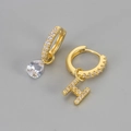Detail van gouden asymmetrische oorbellen met een druppelsteen en een H-hanger - Koper / Goud-Letter H
