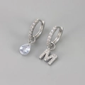 Detail van asymmetrische oorbellen met waterdruppelsteen en ingelegde letter M-hanger - Koper / Zilver-Letter M